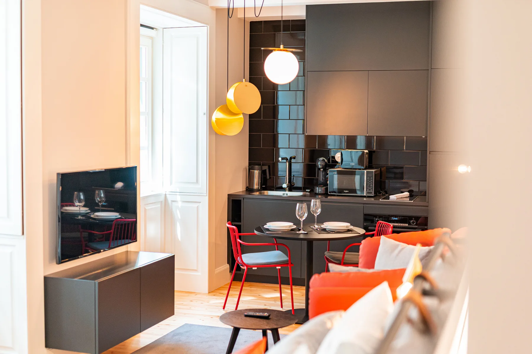 Una pequeña zona de estar tipo estudio con mesa de comedor, asientos y cocina.