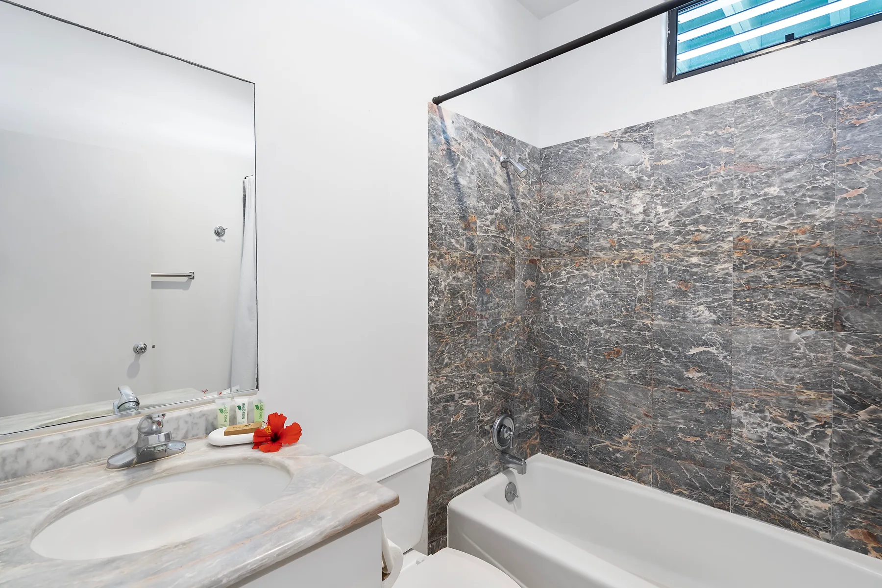 Un baño con un lavabo junto a una bañera y paredes revestidas.
