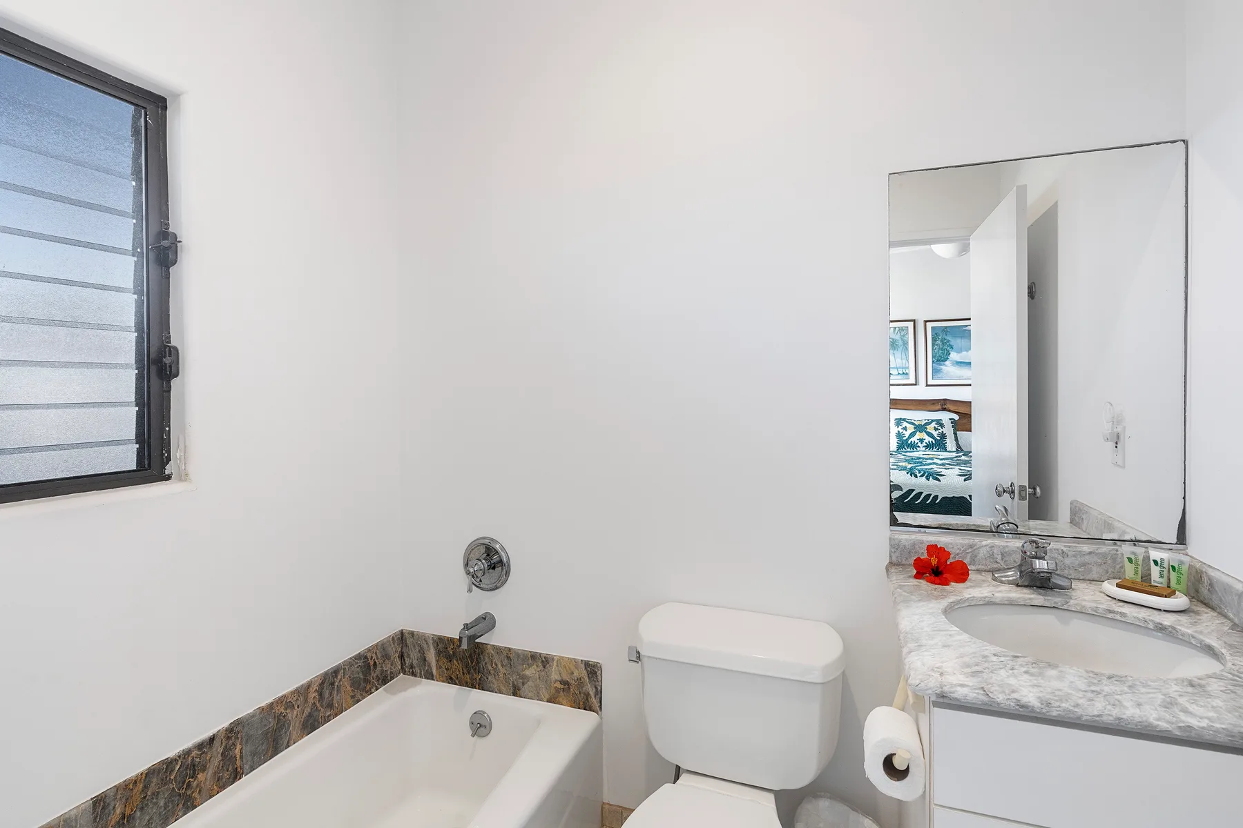 Un baño con bañera, inodoro y lavabo bajo un espejo.