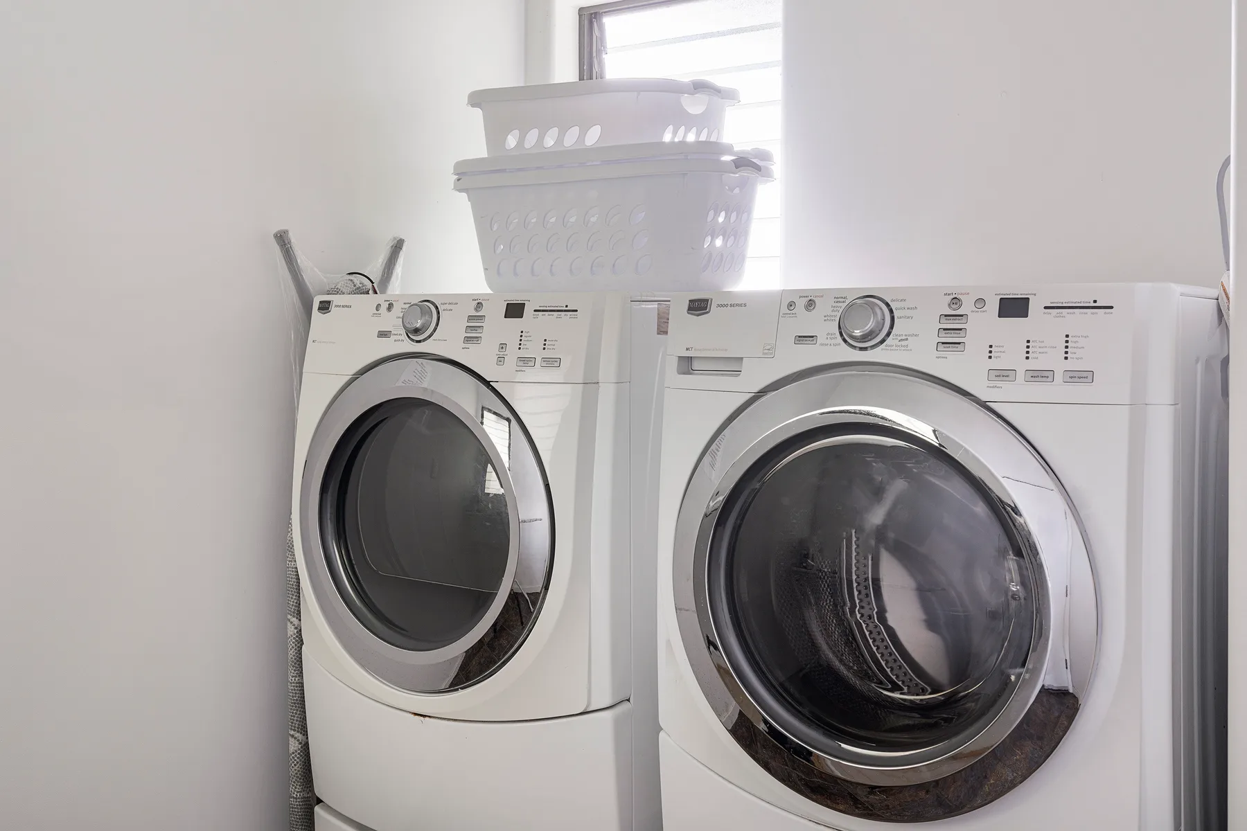 Lavadero con una lavadora y una secadora bajo una ventana.