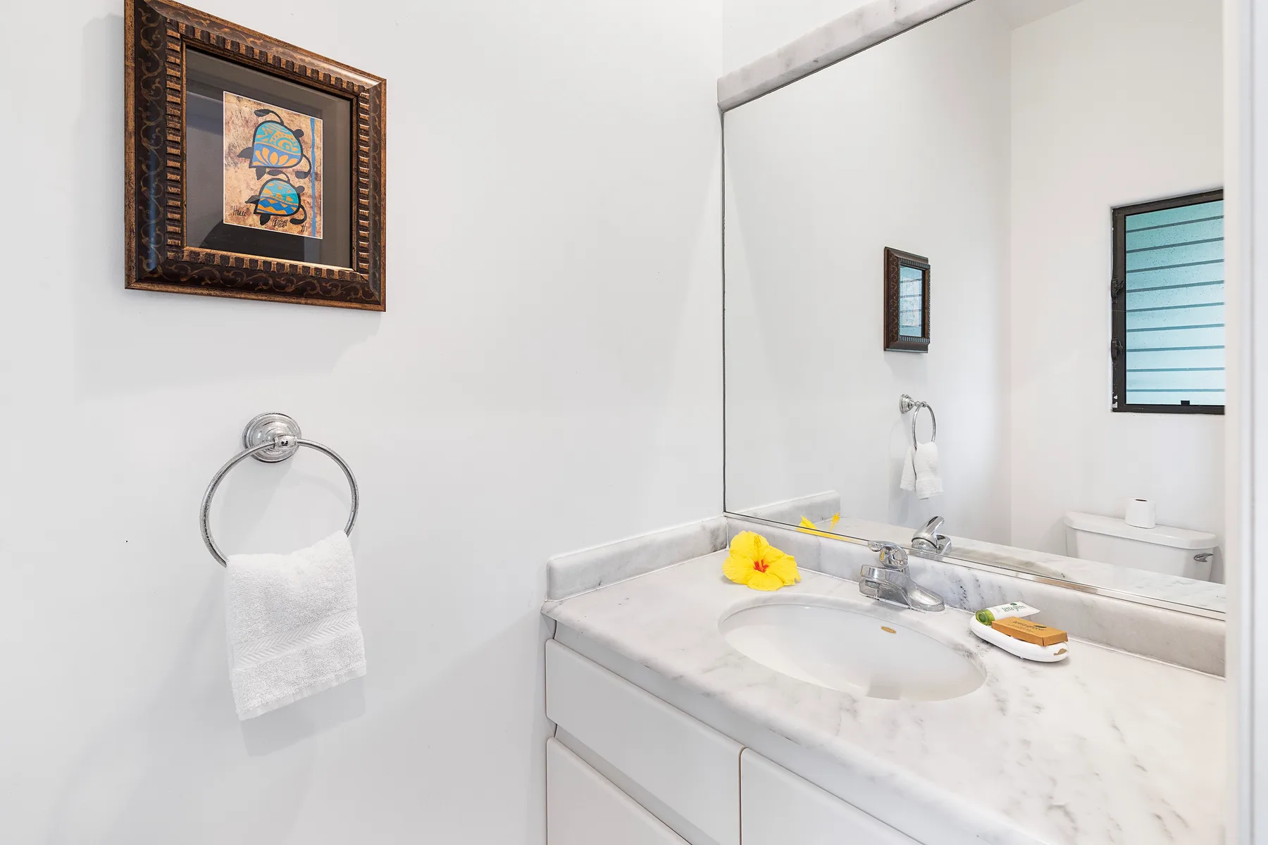 Un tocador de baño con lavabo, espejo de pared y toalla de manos.