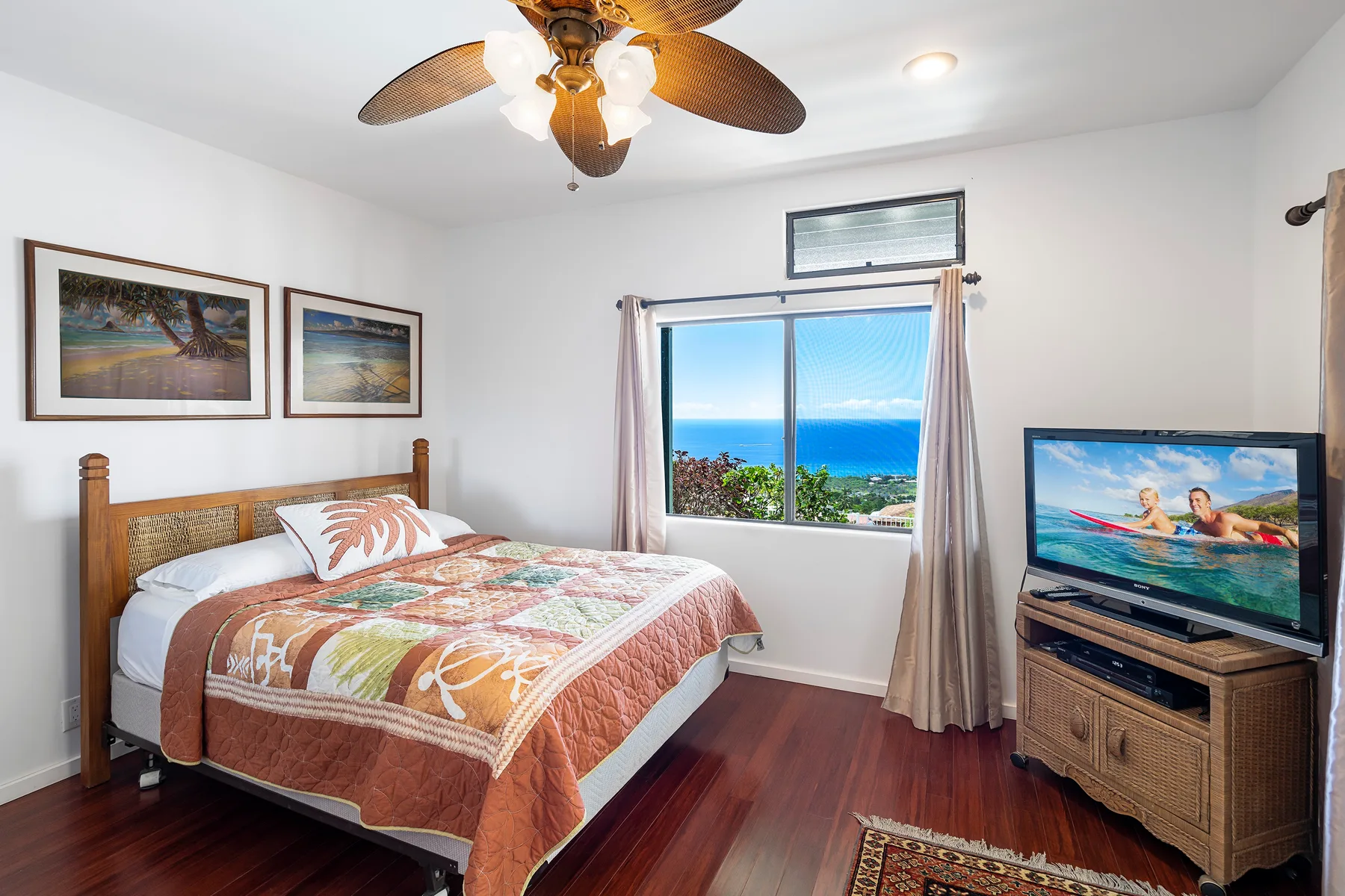 Un dormitorio con una cama, cuadros enmarcados y una ventana con vista al océano.