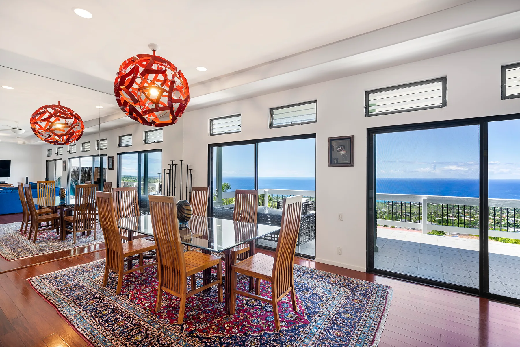 Comedor con mesa de cristal y grandes ventanales con vistas al mar.