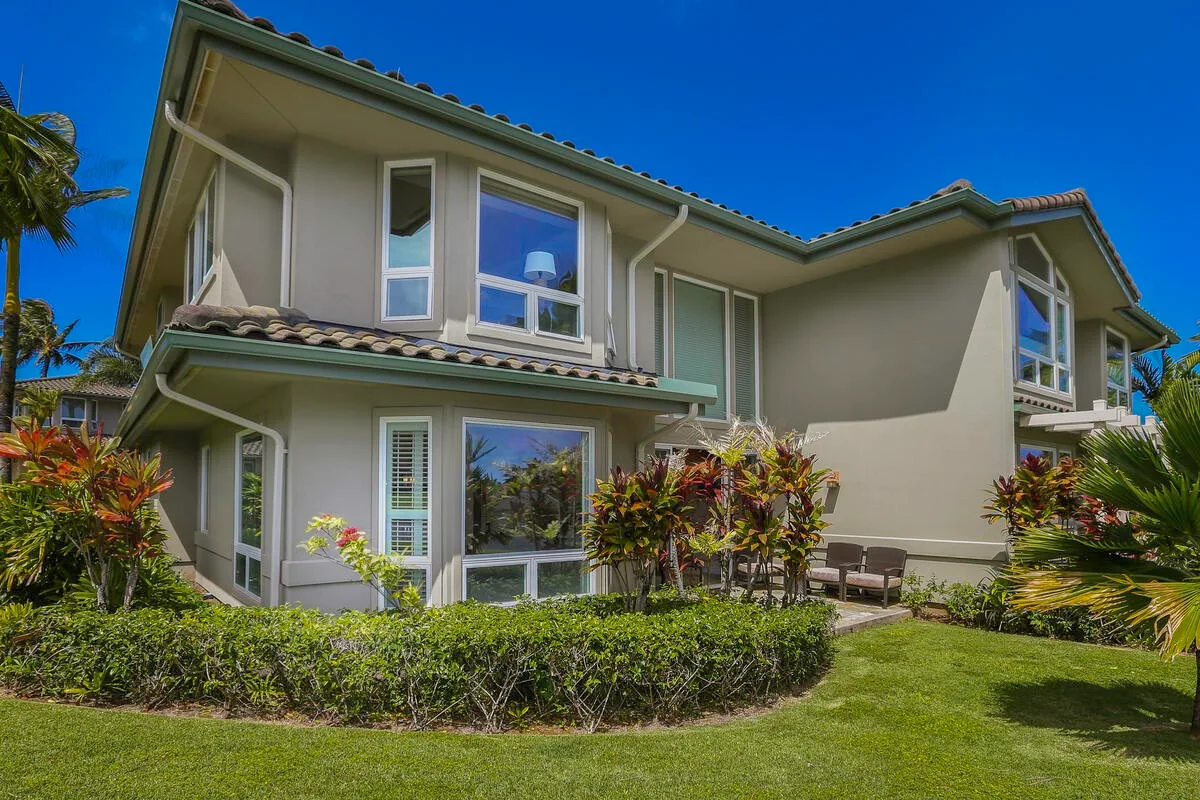 A two-story residential building stands beside a landscaped lawn.
