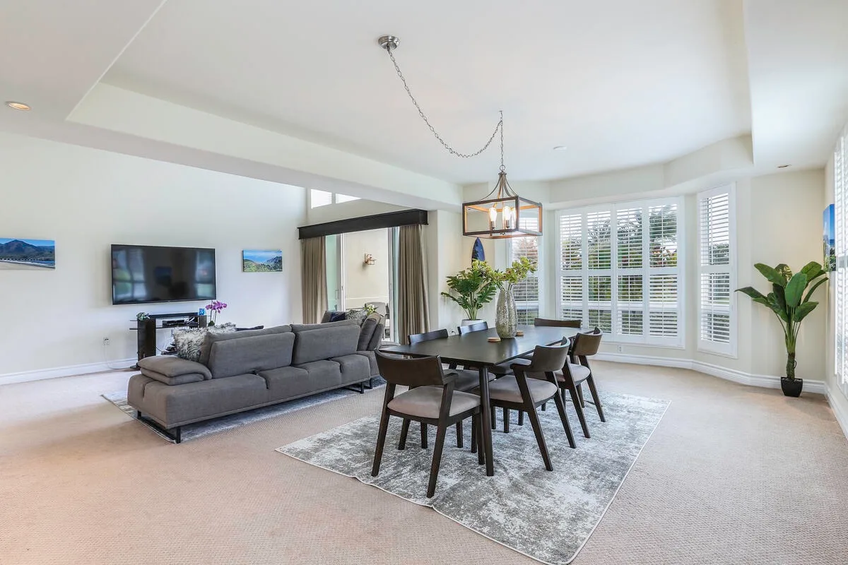 A bright living and dining area with a gray seating arrangement and dining table.