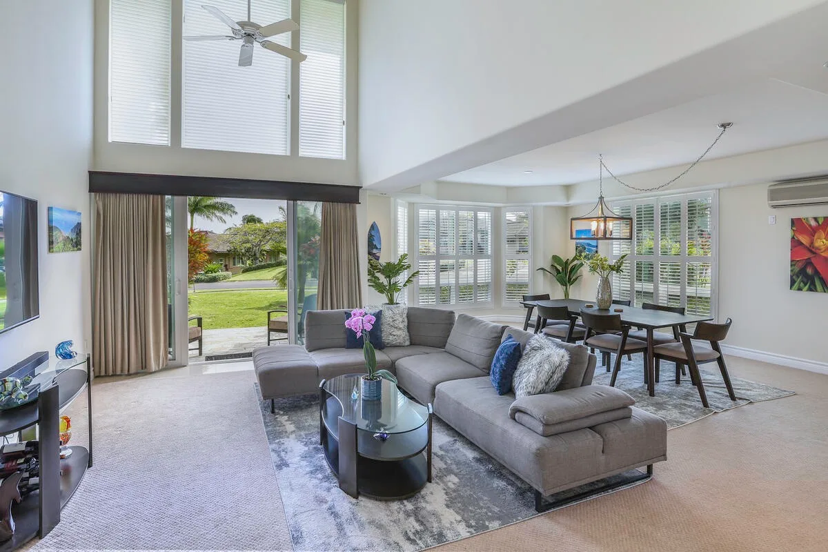 A bright living and dining area with gray seating and a table beside large windows.