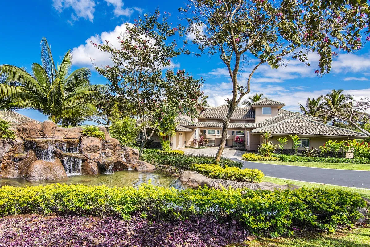 A landscaped residential building stands behind a garden pond and waterfall.