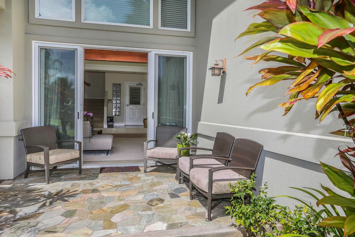 A sunny patio with cushioned seating outside open glass doors.