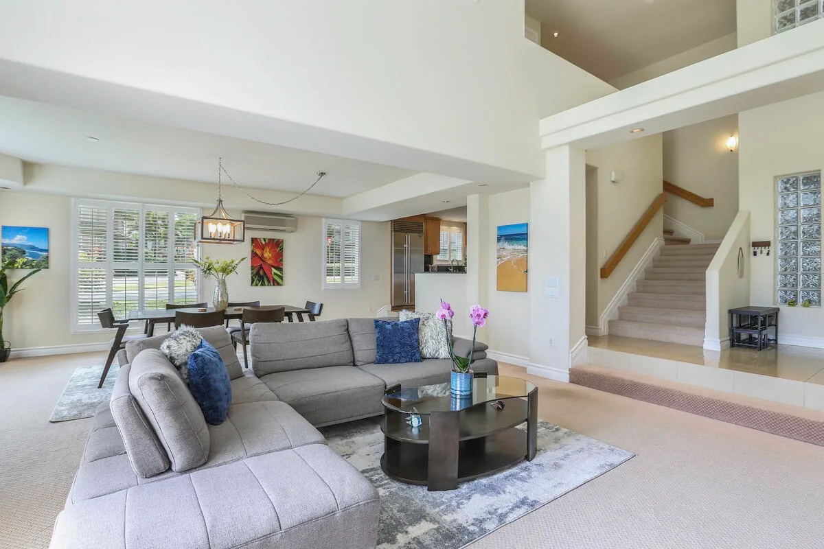An open living room with sectional seating, a coffee table, and a dining area.