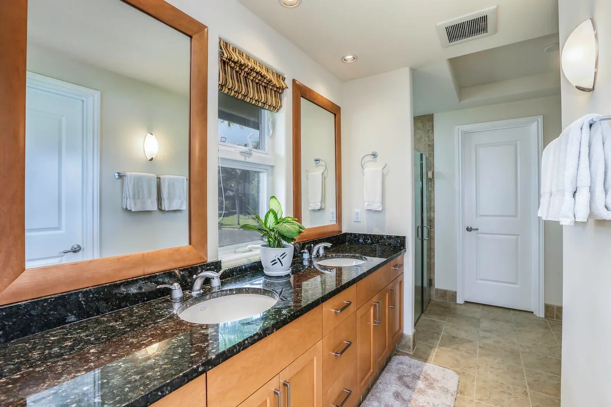 A bright bathroom with a long vanity and a window above the sink.
