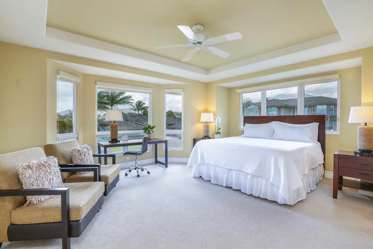 A bright bedroom with a large bed, seating, and wide windows.