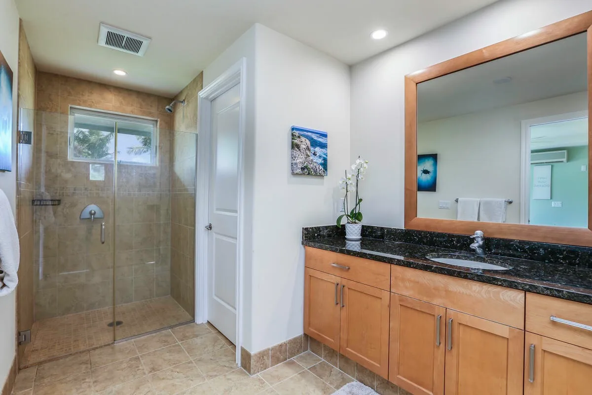 A bathroom with a glass shower and a long vanity beneath a large mirror.
