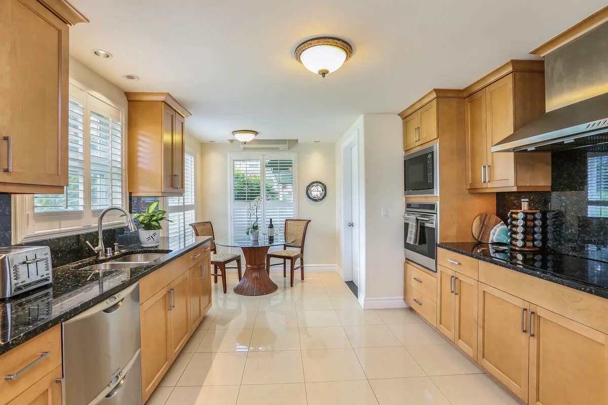 A bright kitchen with wooden cabinets and a small dining table by the windows.