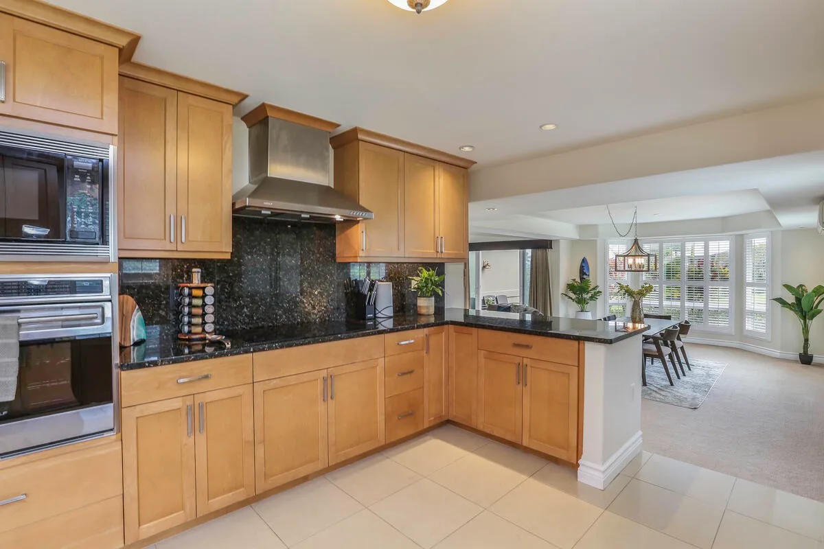 A bright kitchen with wooden cabinets and a counter opening onto a dining area.