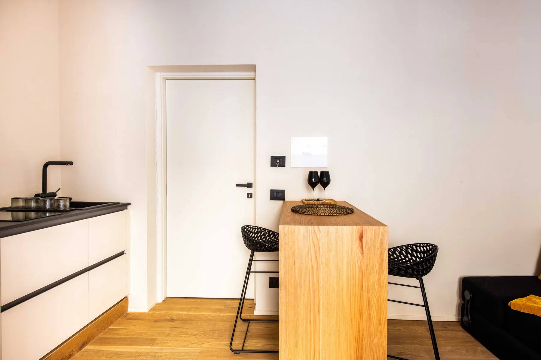 Un comedor luminoso tiene una mesa de madera, dos asientos y una puerta blanca.