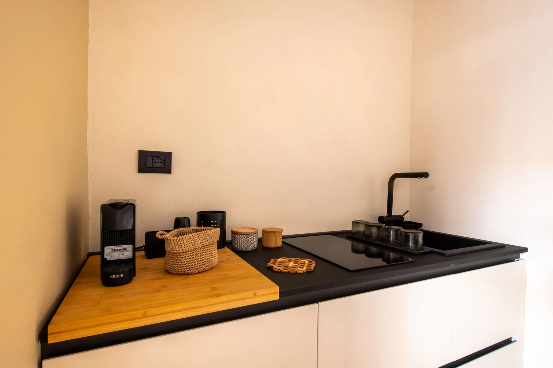 A compact kitchen counter with a sink, cooktop, and wooden work surface.