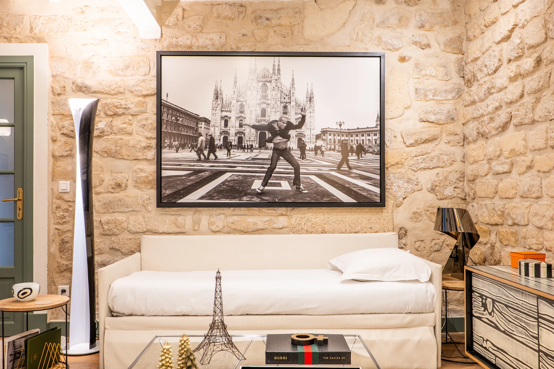 A bedroom with a neatly made bed against a textured stone wall.