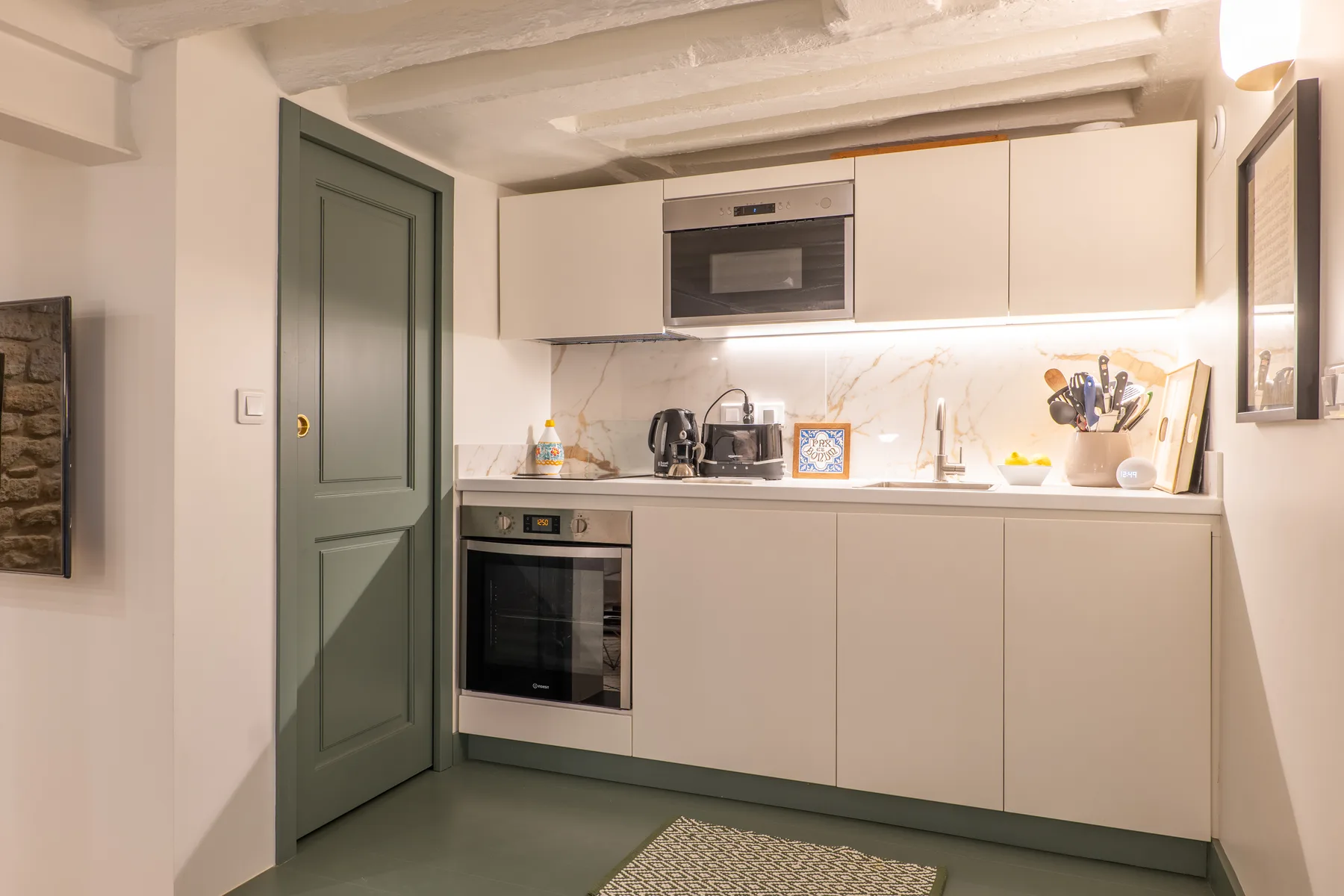 A compact kitchen with pale cabinets, a built-in oven, and countertop appliances.