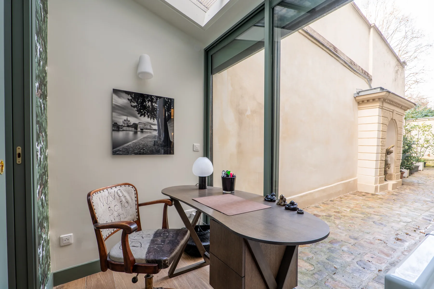 A small seating area beside large glass doors opens onto a paved courtyard.