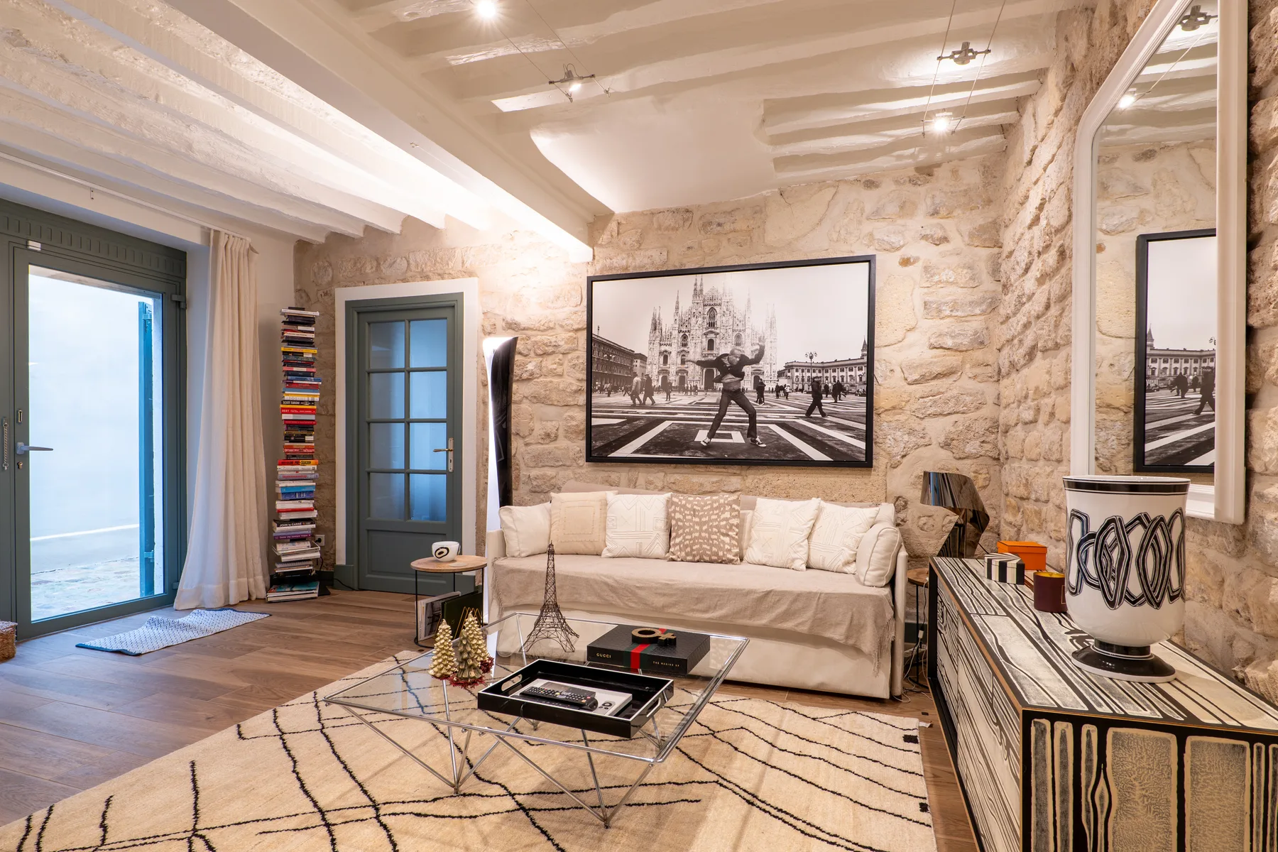 A living room with a light-colored sofa, glass coffee table, and stone walls.