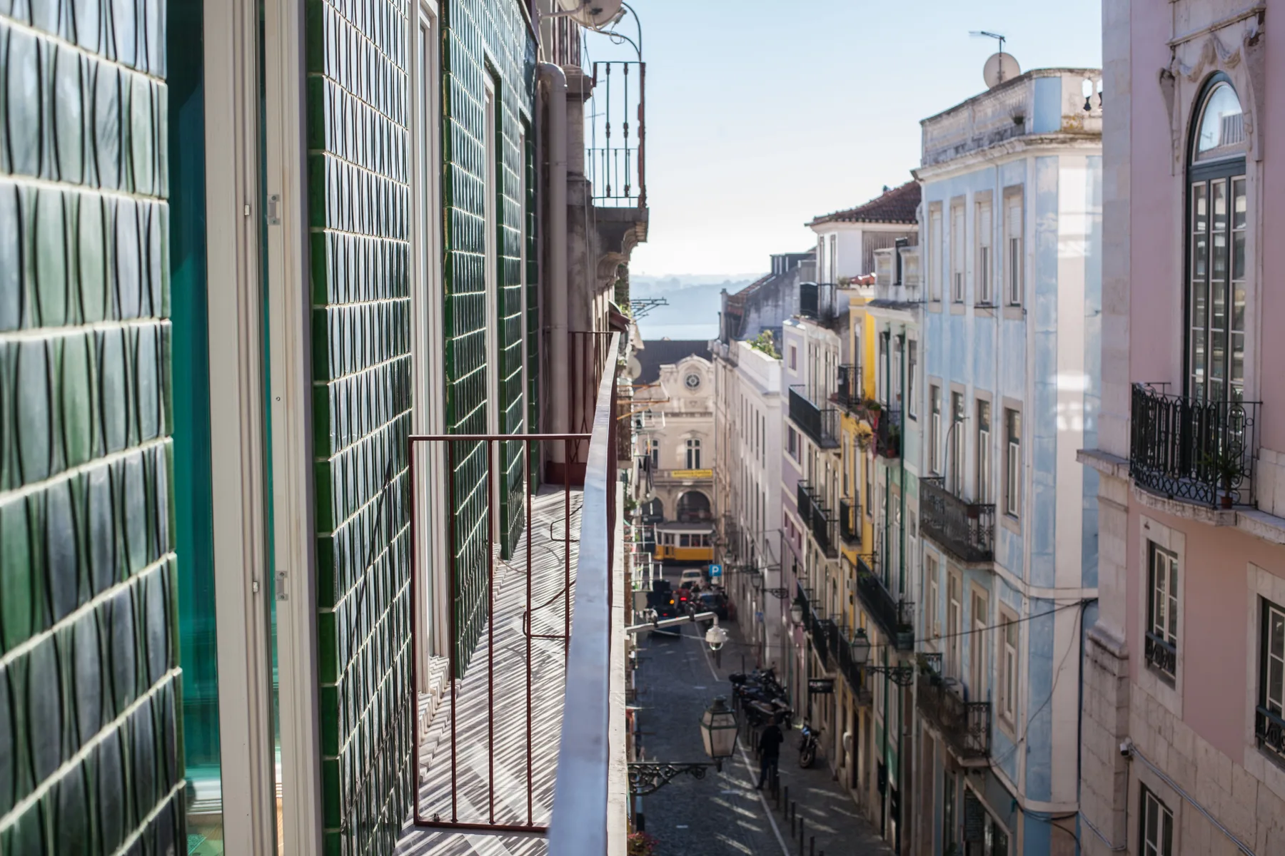 Una calle estrecha corre entre edificios altos, con agua visible a lo lejos.