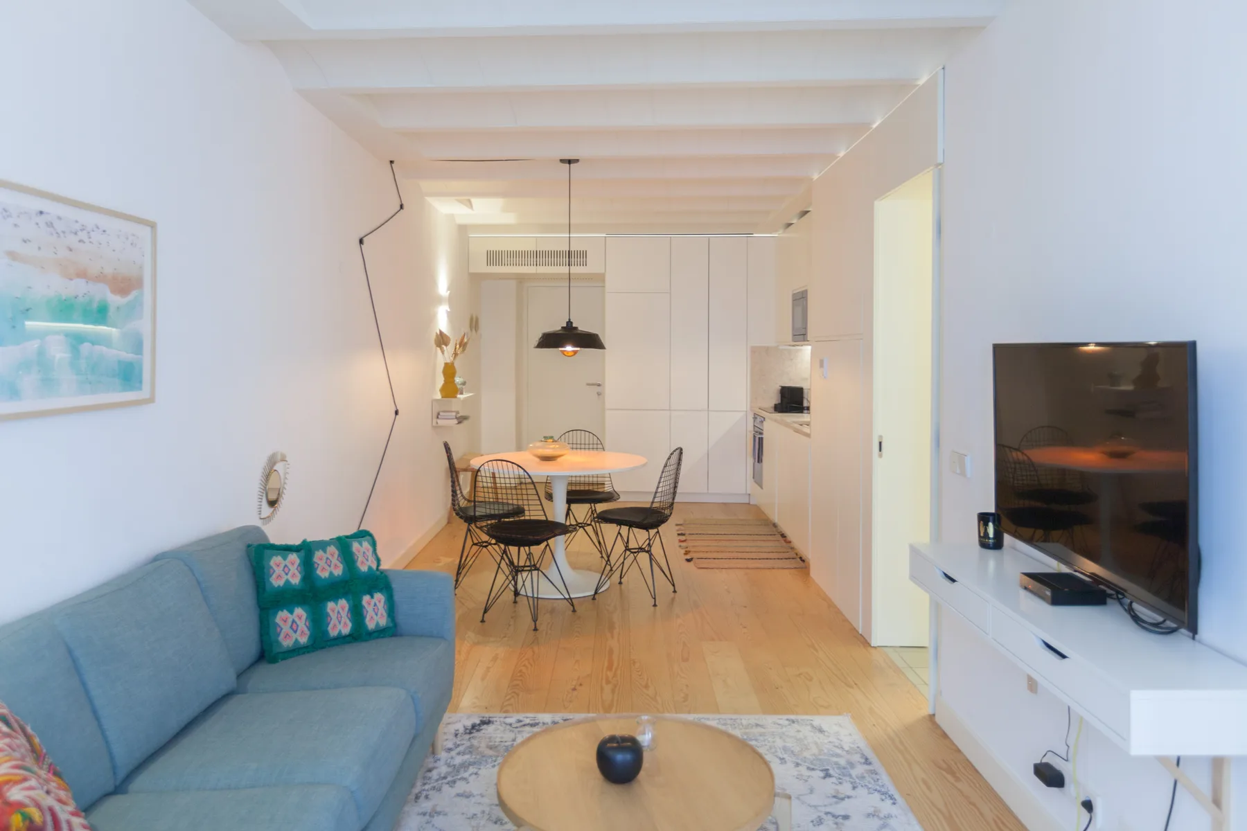 Una luminosa sala de estar y comedor con asientos, una mesa y un televisor.