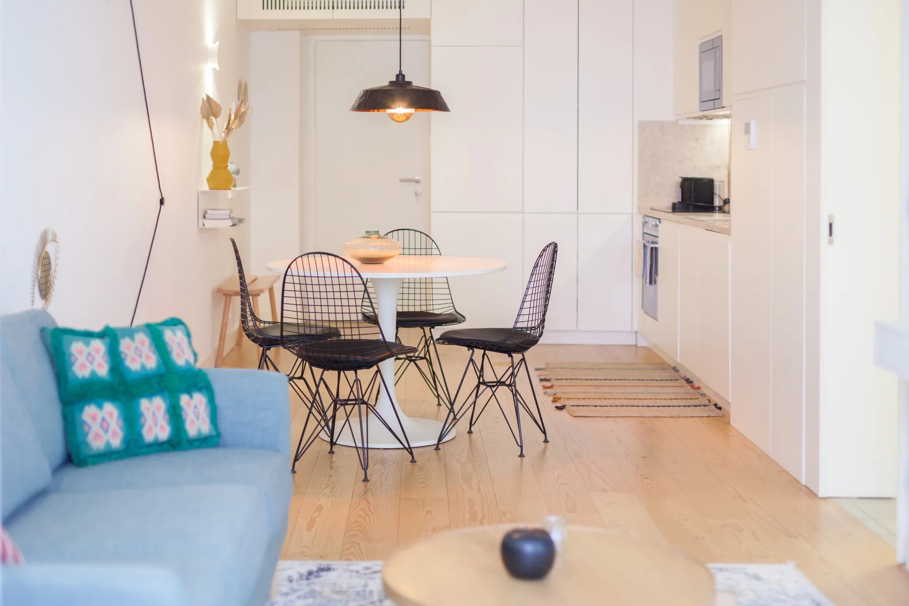 Un comedor luminoso con una mesa redonda y una cocina compacta.