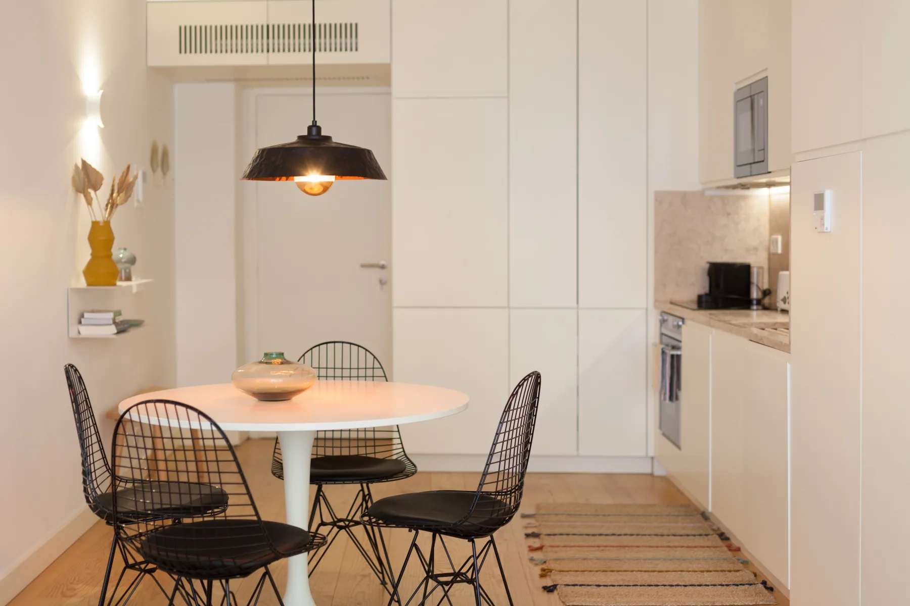 Un comedor luminoso con una mesa y sillas junto a una cocina compacta.