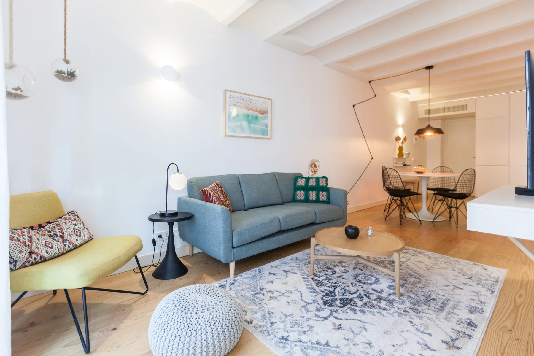 Una sala luminosa con asientos y un comedor al fondo.