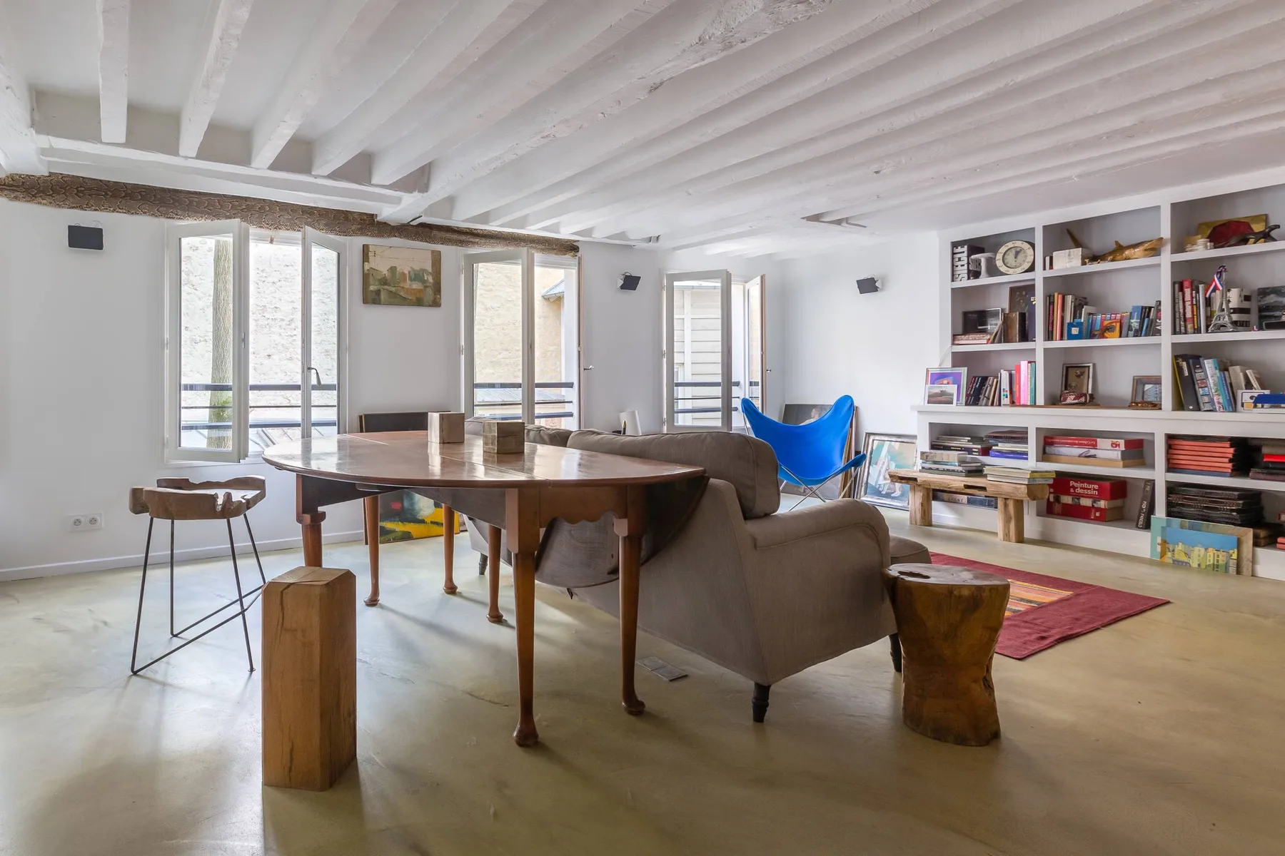 Una luminosa sala de estar y comedor con mesa de madera, asientos y estanterías.
