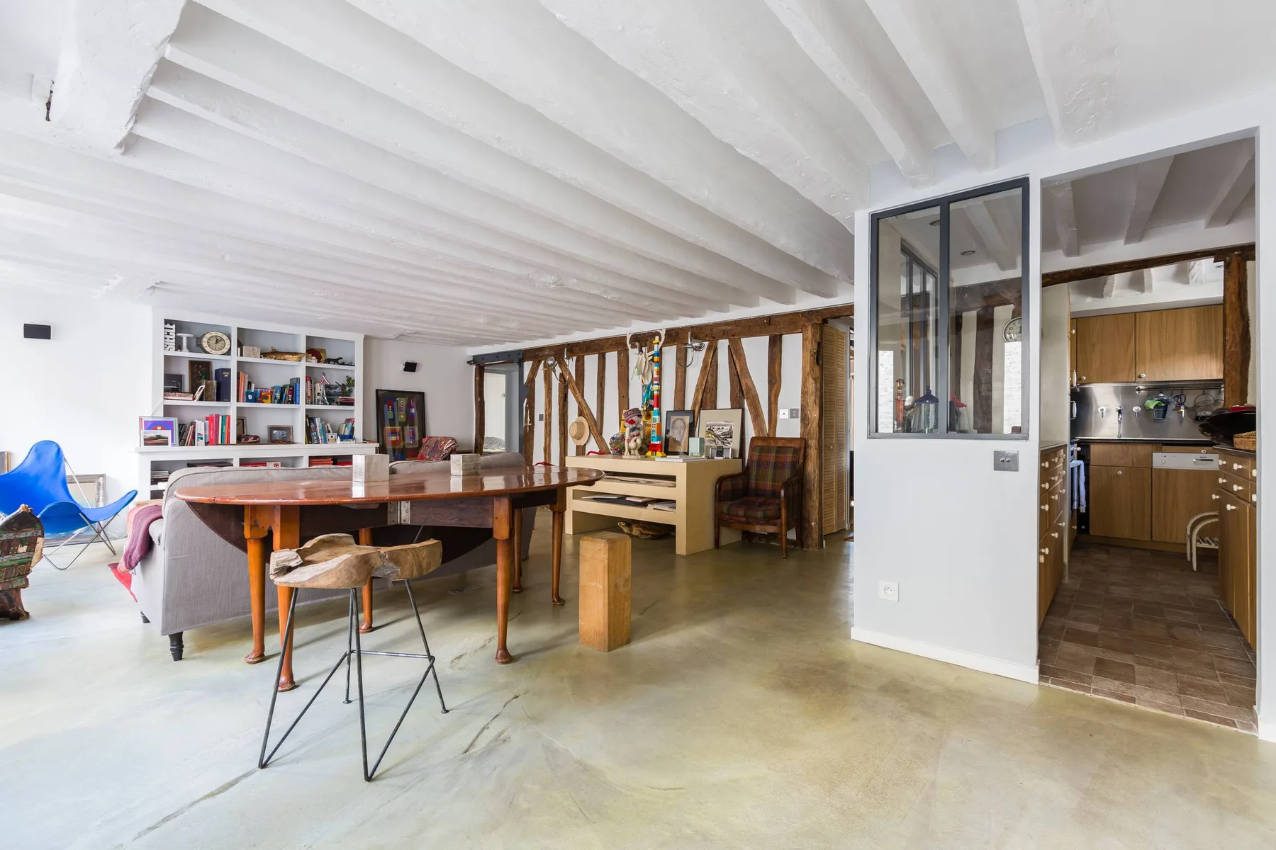 Un espacio abierto de comedor y sala con una mesa de madera y estanterías.