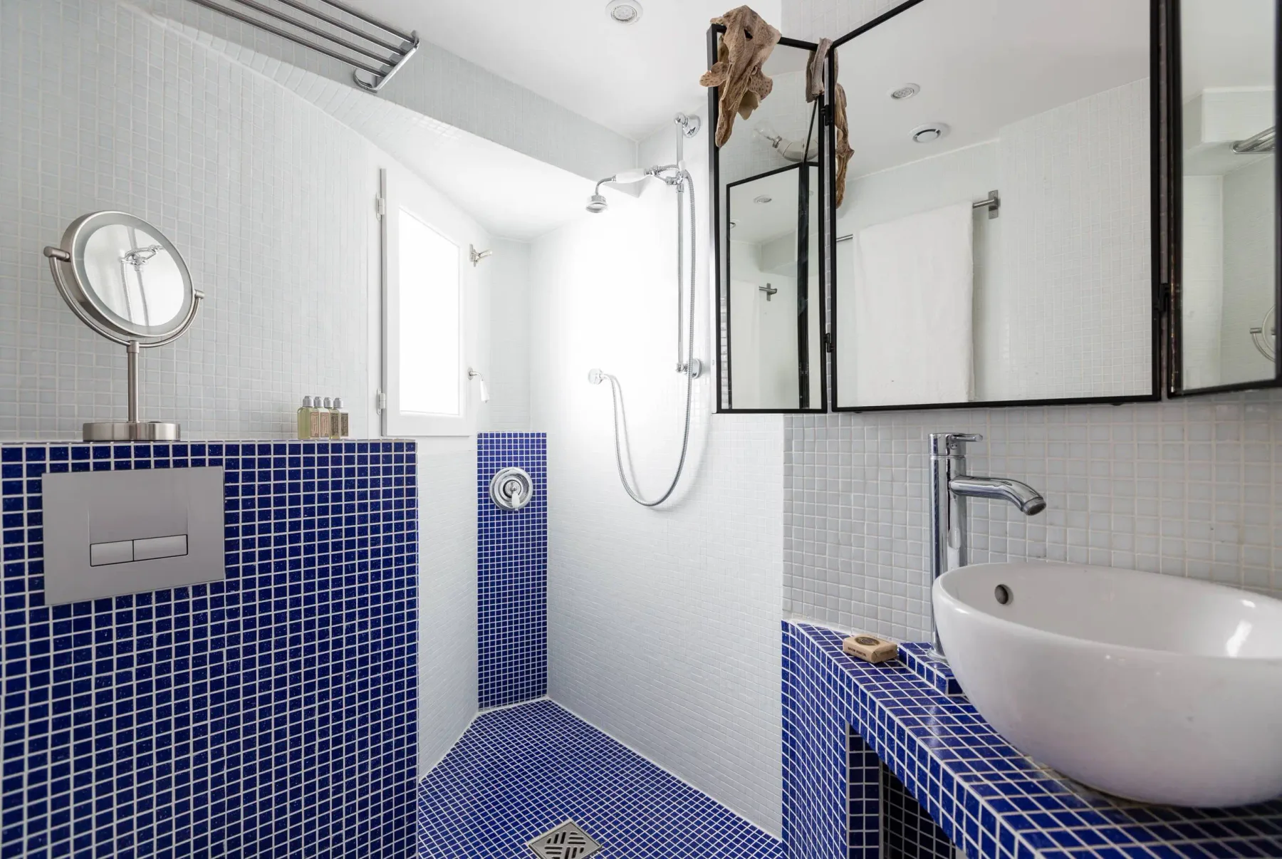 Un baño alicatado con ducha de pared y lavabo sobre encimera.