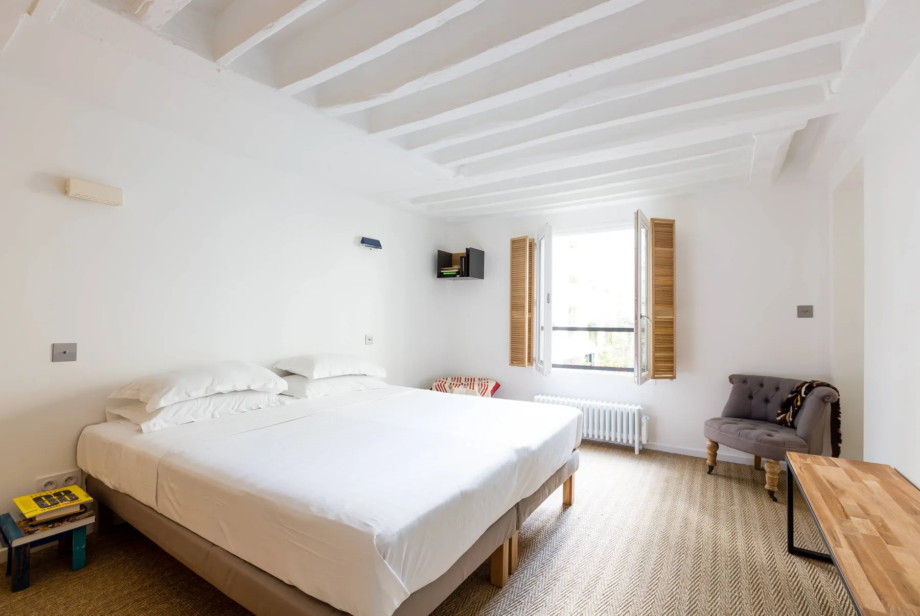 Un dormitorio luminoso tiene una cama grande, una ventana y asientos.