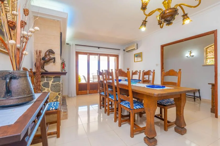 A dining room with a wooden table and chairs beside bright glass doors.