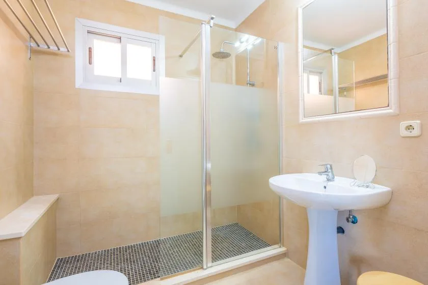 A tiled bathroom with a glass shower and a sink beneath a mirror.