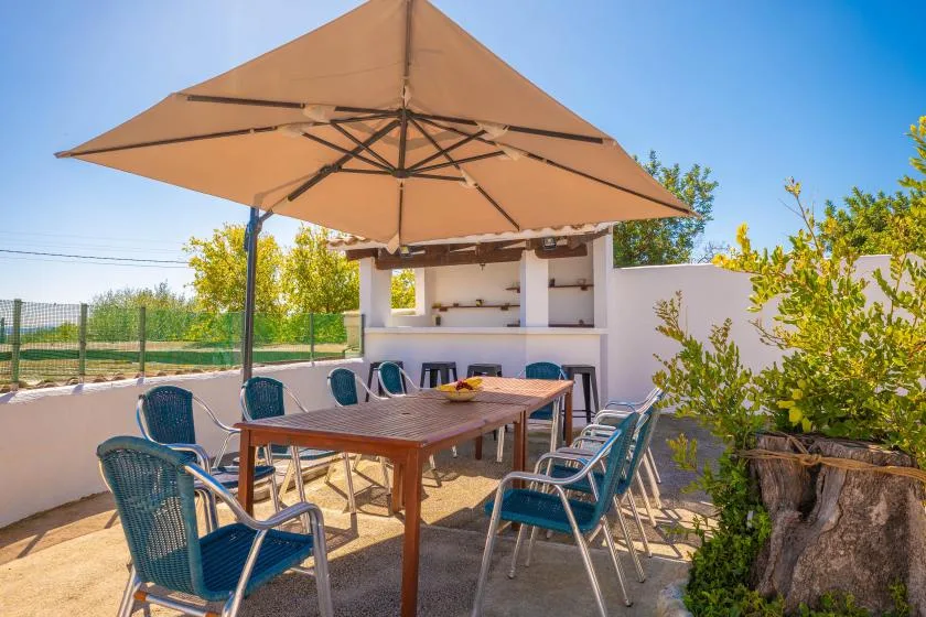 An outdoor dining area with a large umbrella shading a table and seating.
