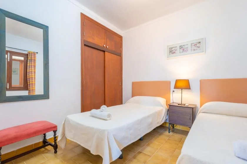 A bedroom with two beds, a bedside table, and a framed wall print.