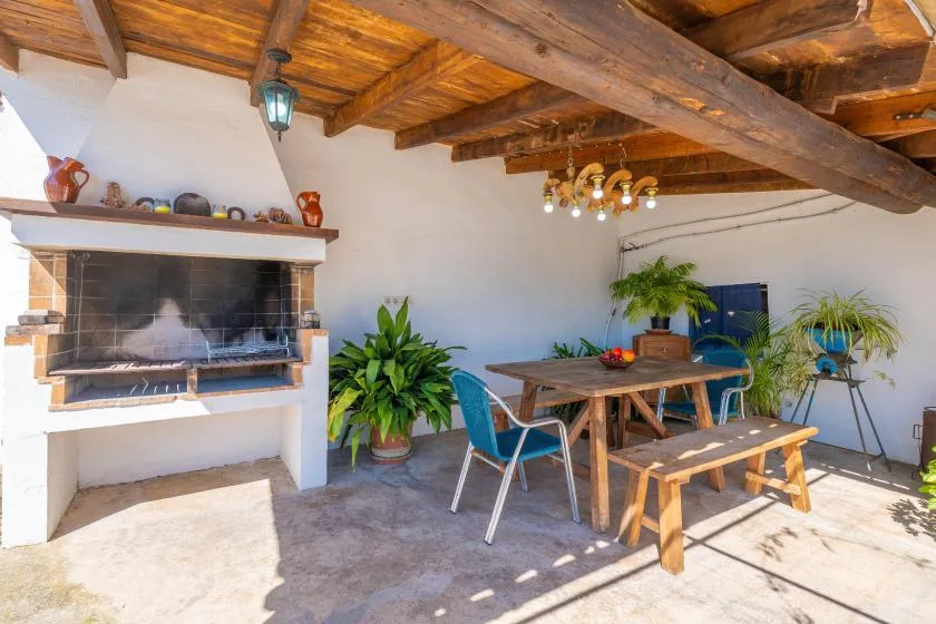 A rustic dining area with a wooden table, benches, and a large fireplace.