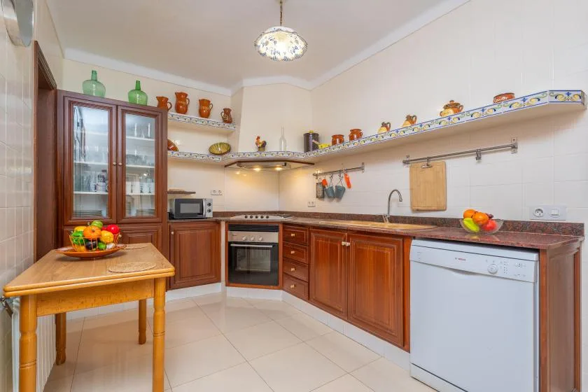 A kitchen with wooden cabinets, a countertop, and a small dining table.
