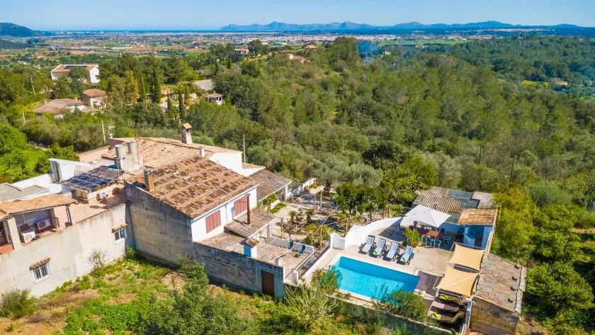 An aerial view of a countryside property with a swimming pool amid green hills.
