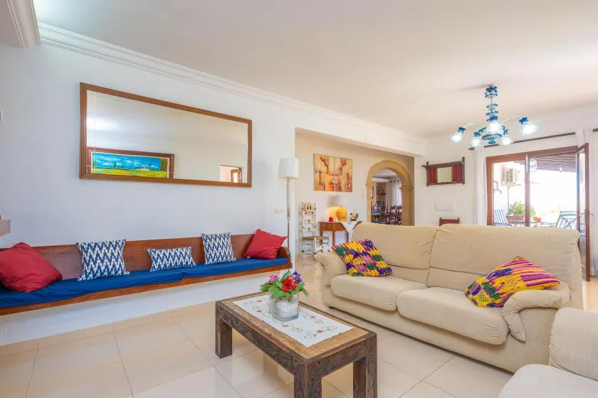 A bright living room with a beige sofa and a long cushioned bench.
