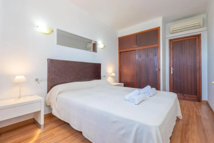 A bedroom with a neatly made bed and wooden wardrobe.