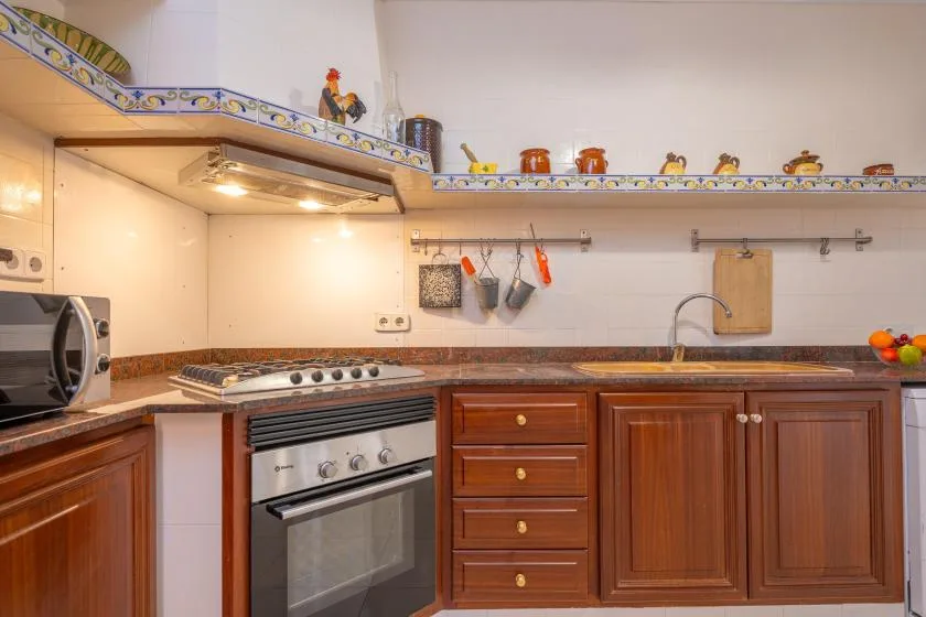 A kitchen with wooden cabinets, a stove, and a sink.