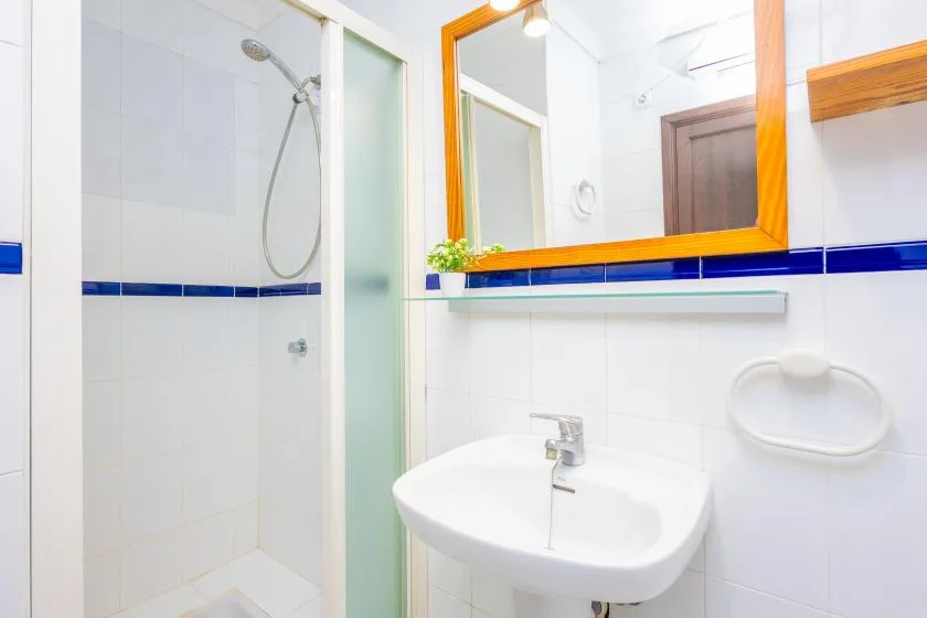 A bright bathroom with a sink, mirror, and glass shower.