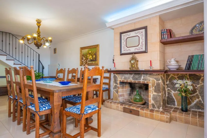 A dining room with a wooden table and chairs beside a stone fireplace.
