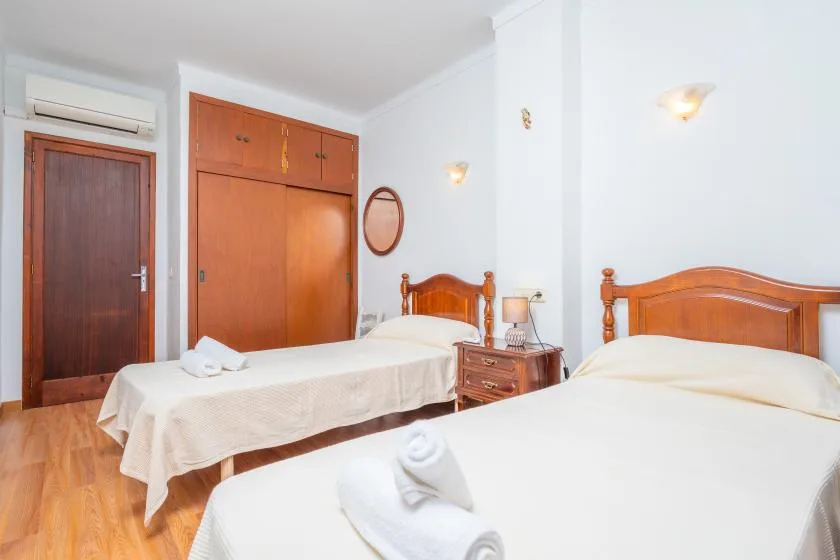 A bedroom with two beds, wooden headboards, and a built-in wardrobe.