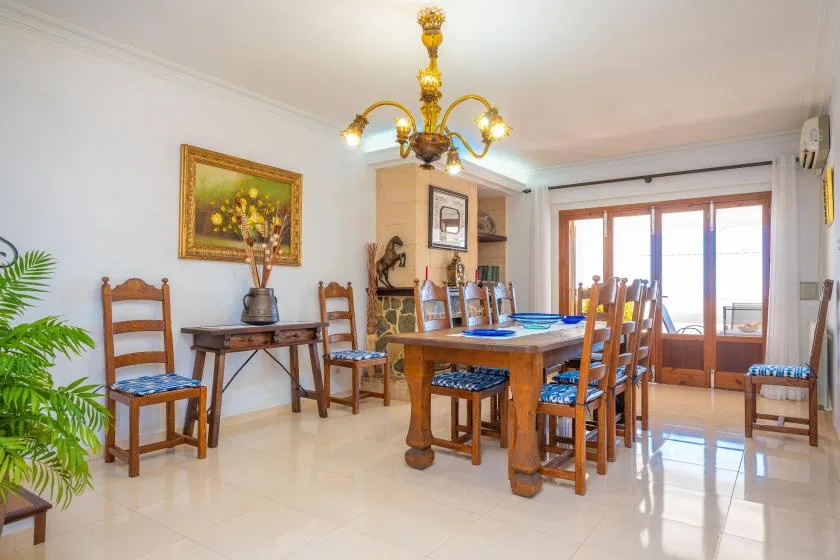 A dining room with a wooden table and chairs beneath a chandelier.
