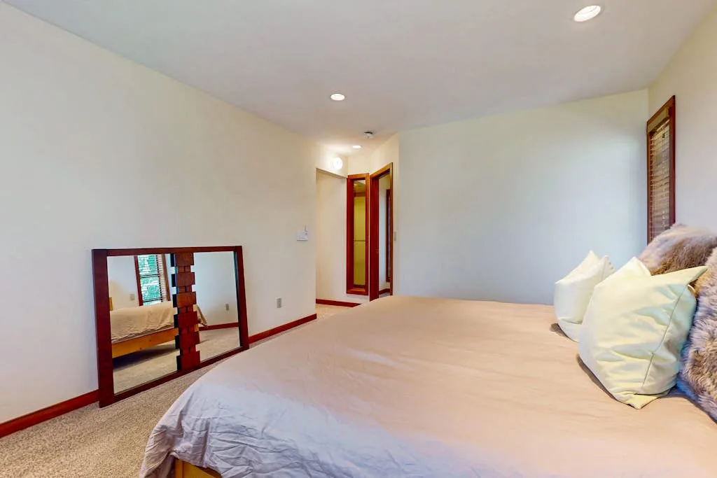 A bedroom with a bed and a low mirror against the wall.
