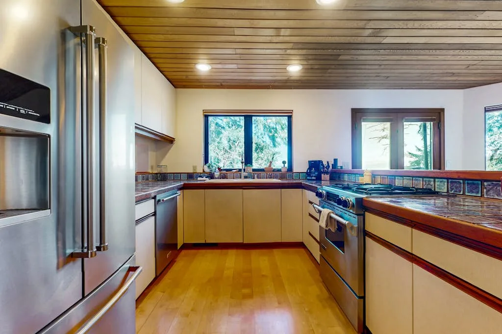 A kitchen with wooden cabinetry, a large central island, and windows along the back wall.