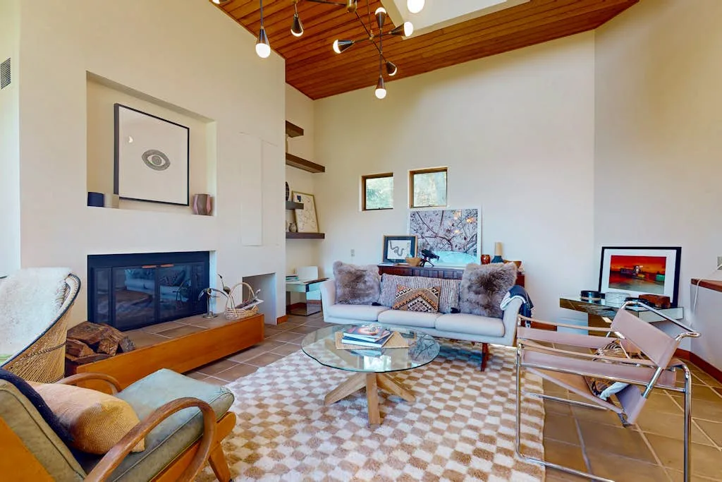 A living room with seating, a fireplace, and a glass coffee table.
